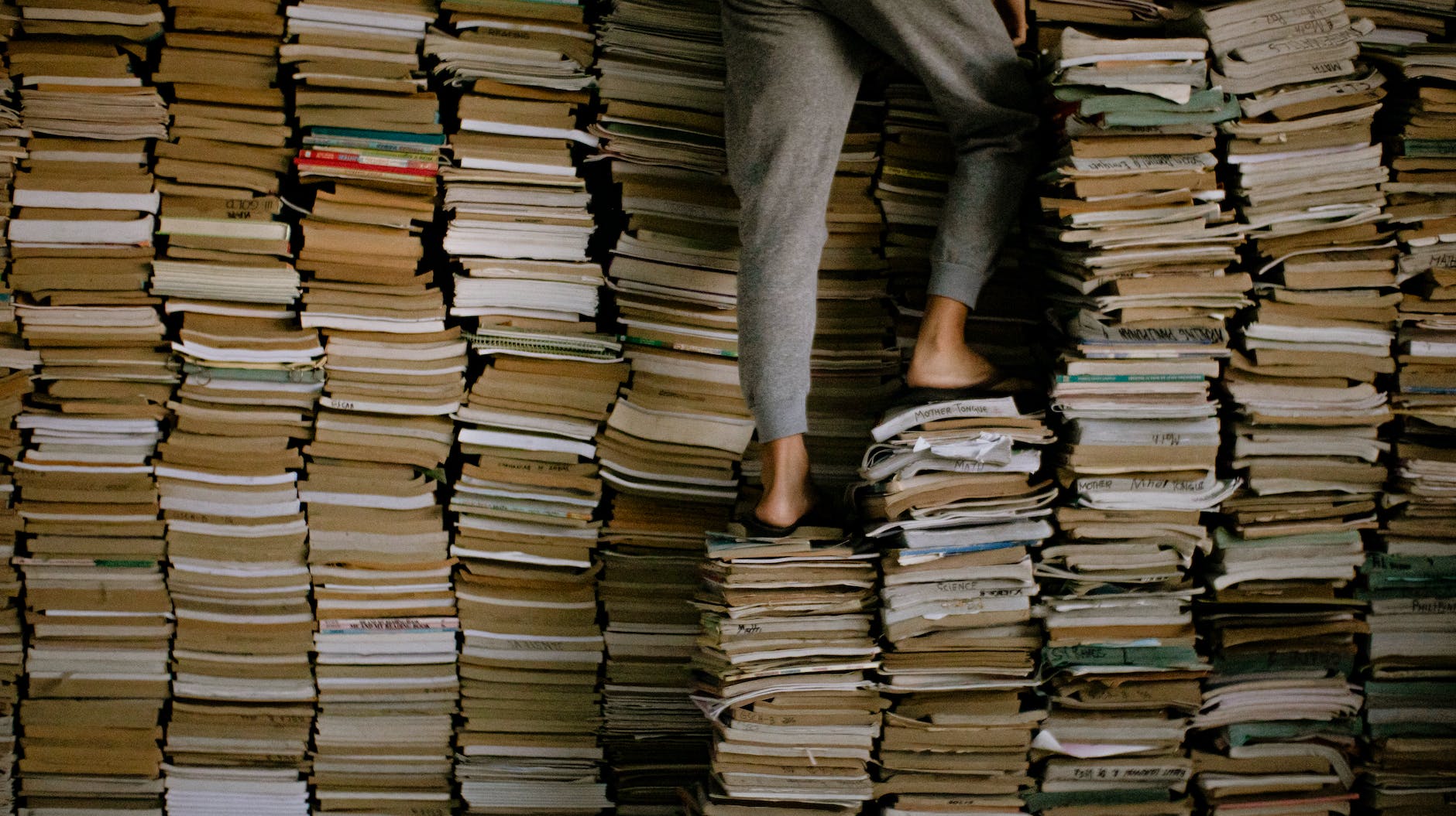 person standing on stacks of books